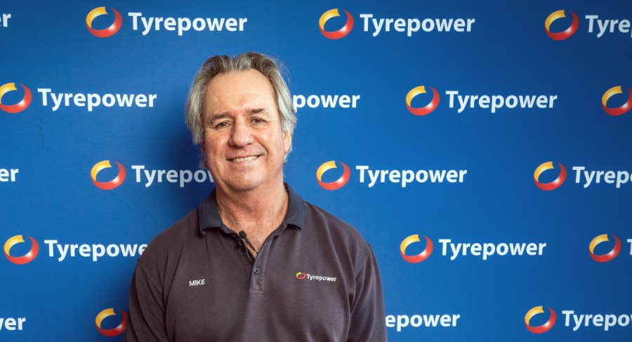 Man and woman dressed in business wear inspecting side of vehicle.