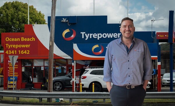 Man and woman dressed in business wear inspecting side of vehicle.