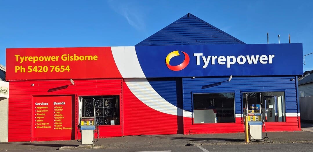 Man and woman dressed in business wear inspecting side of vehicle.